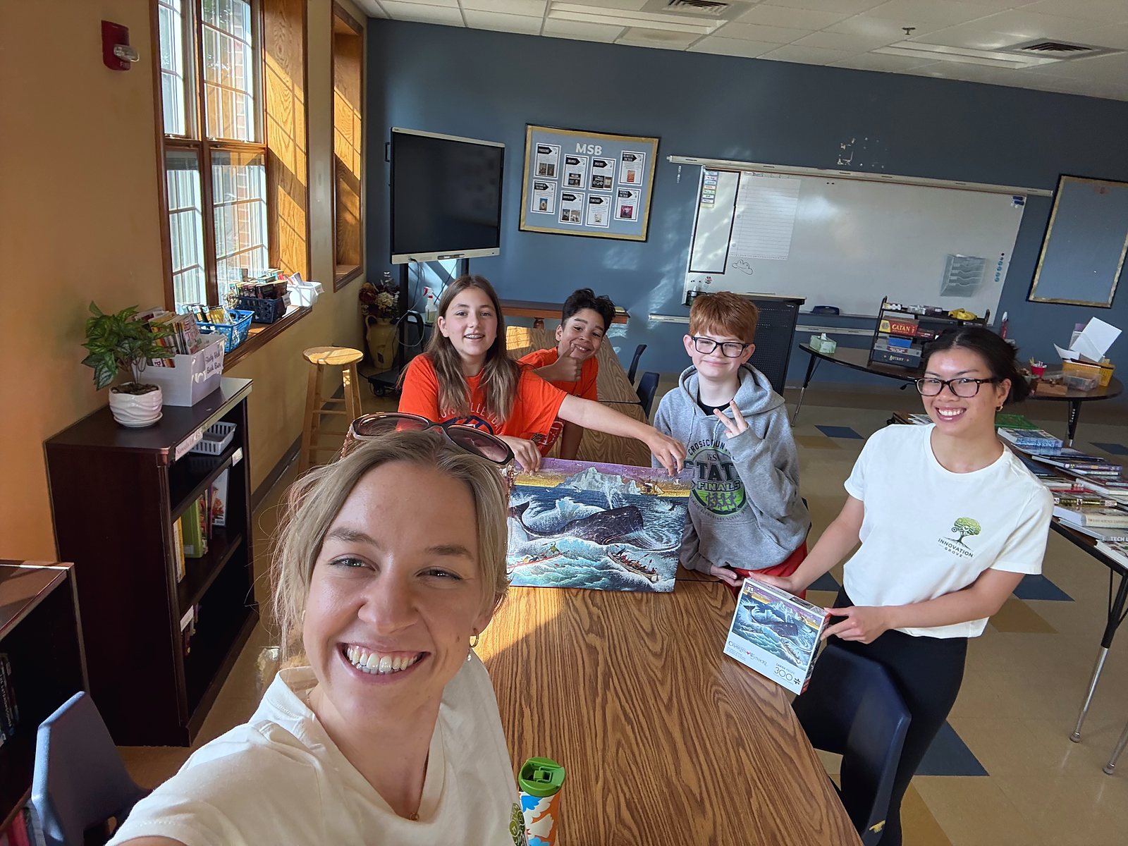 Dr. Sutkus takes a selfie with three students and a counselor over the puzzle they just finished