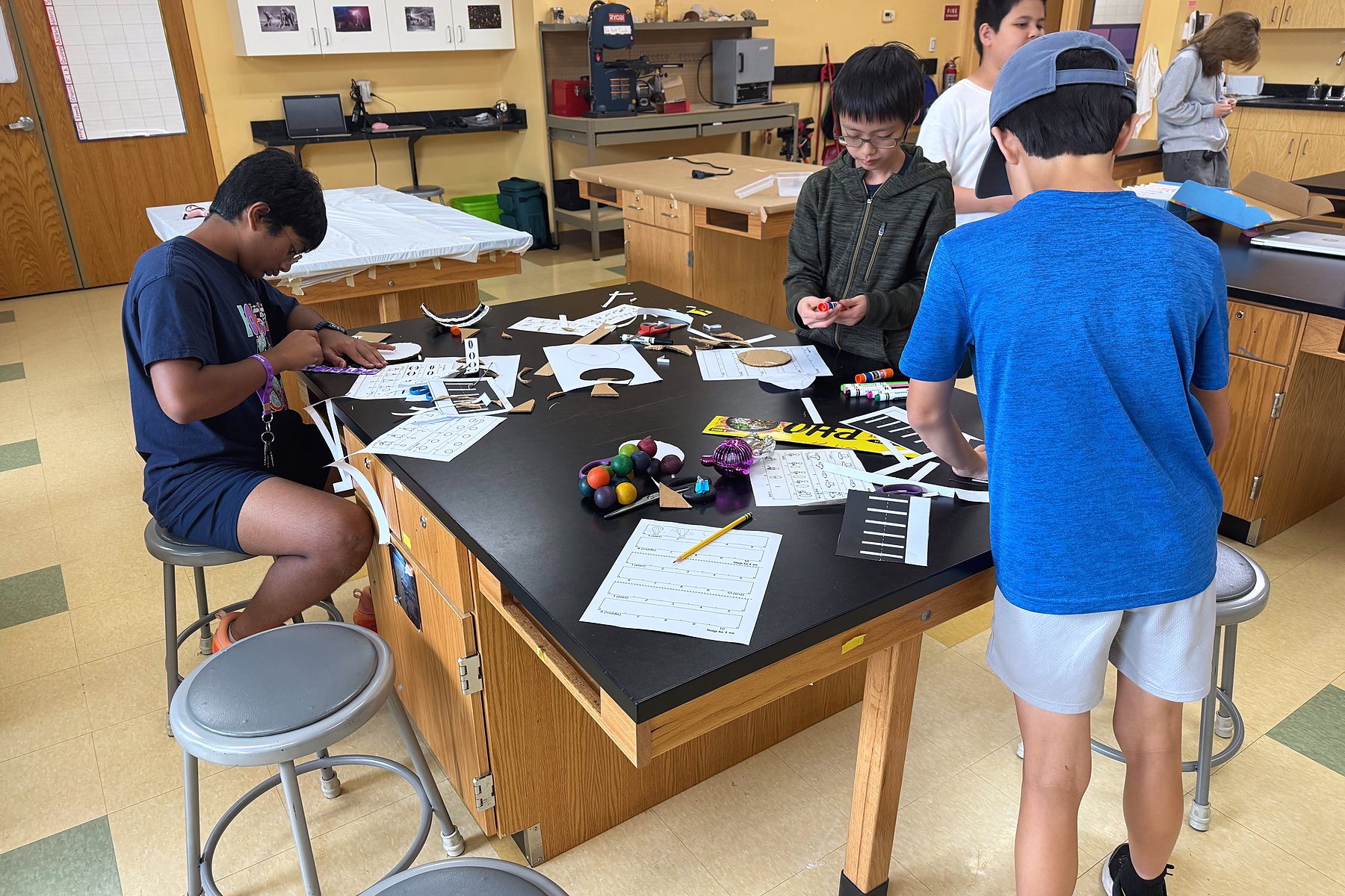Students cutting and assembling optical illusion toys at a work table