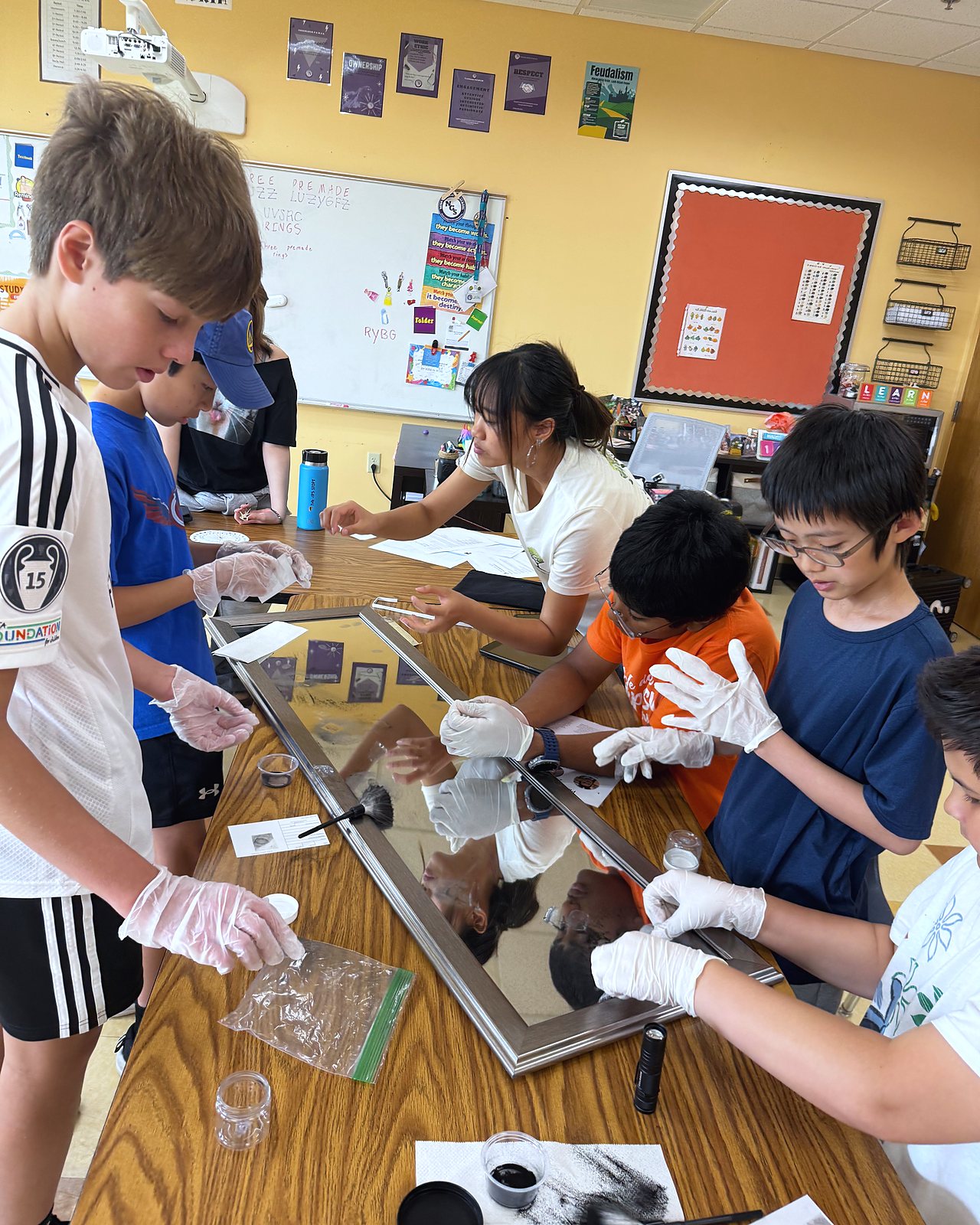 Students in white gloves lift fingerprints from a glass pane during the Mystery Heist