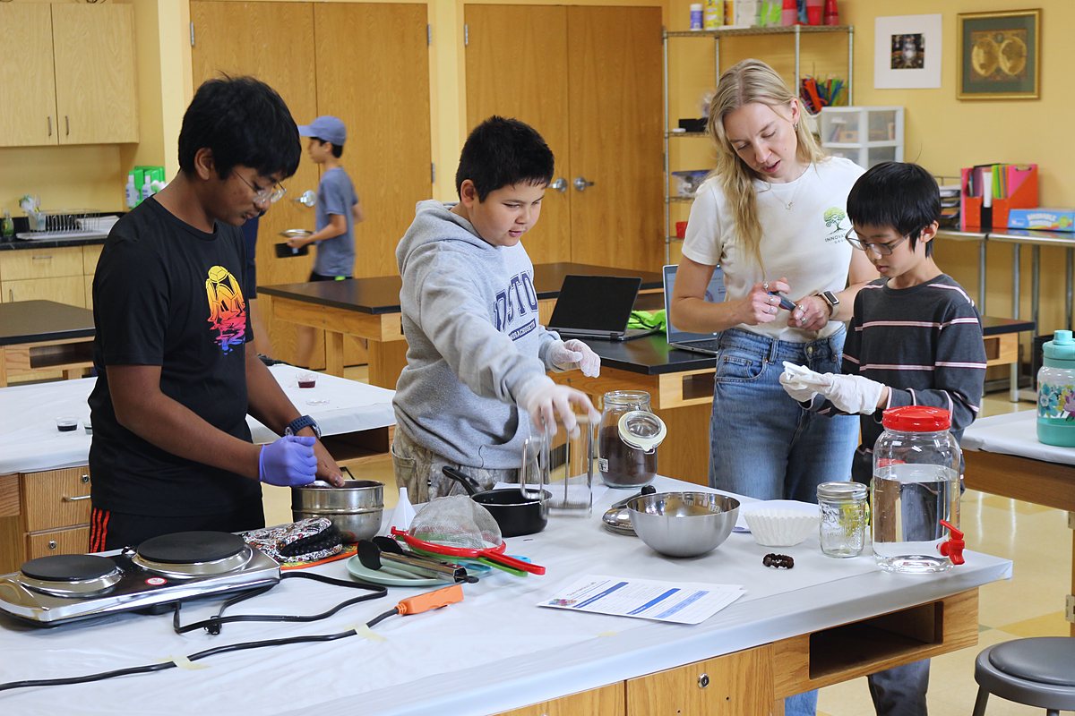 Hot plates, pots and jars of dye on the white-clothed table while students and an instructor work