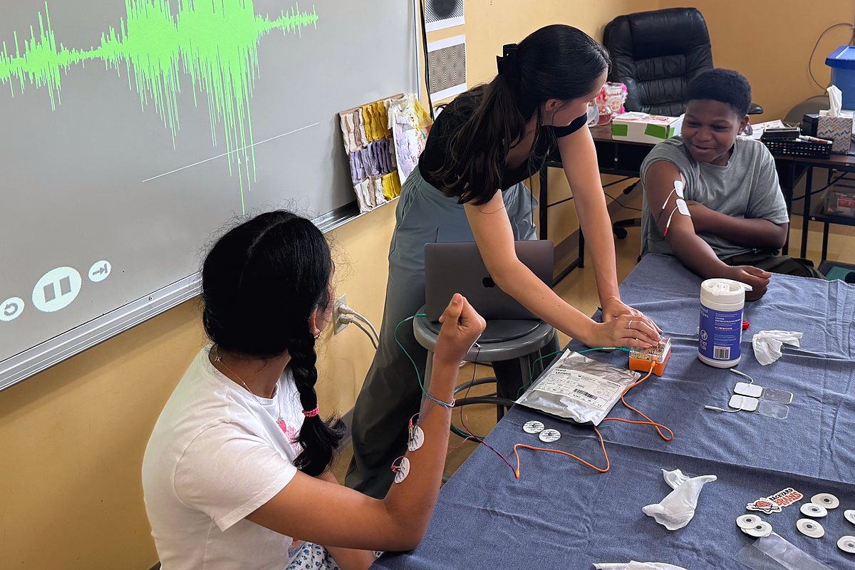 Brain Time: a muscle signal spikes across the screen while an instructor wires an electrode to a student&rsquo;s arm