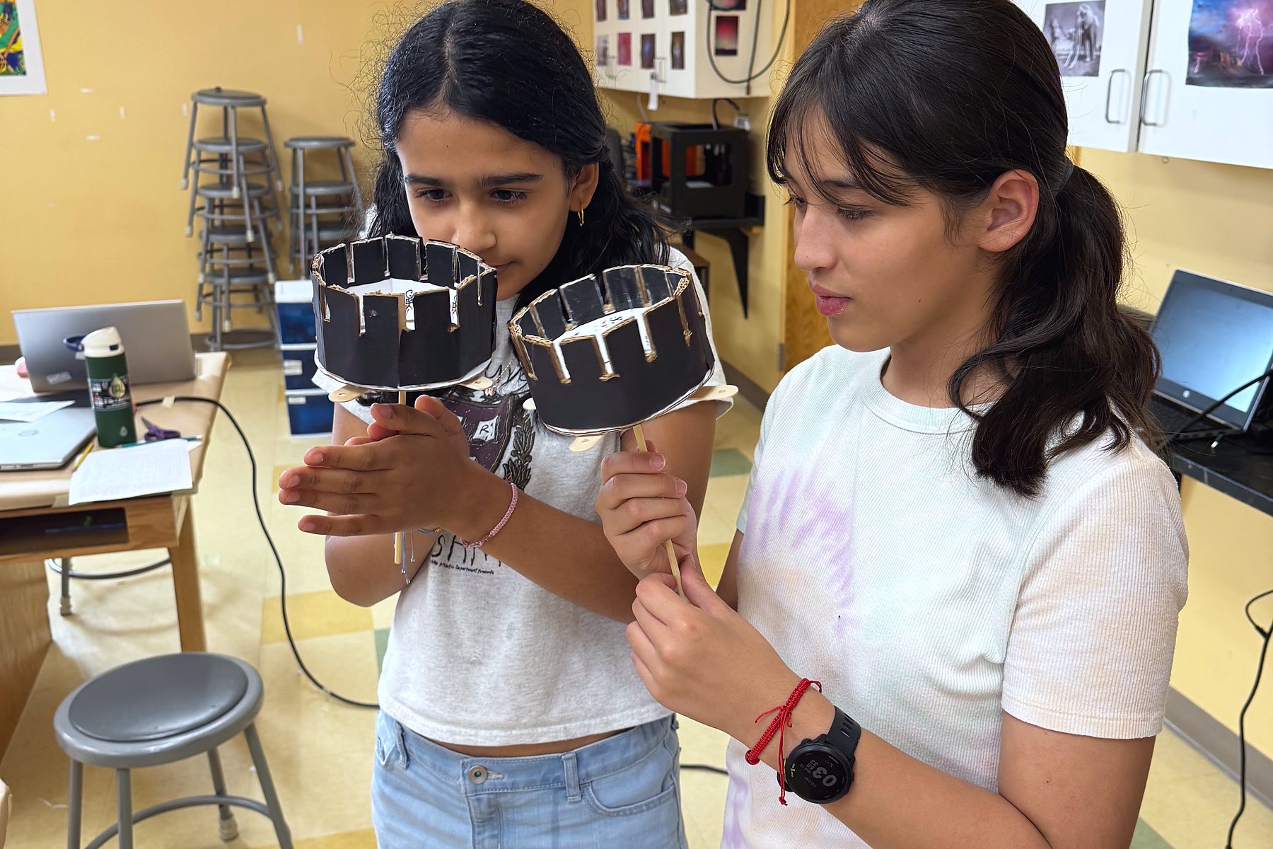 Two students hold up the illusion drums they built in the Eye Spy Illusion Lab