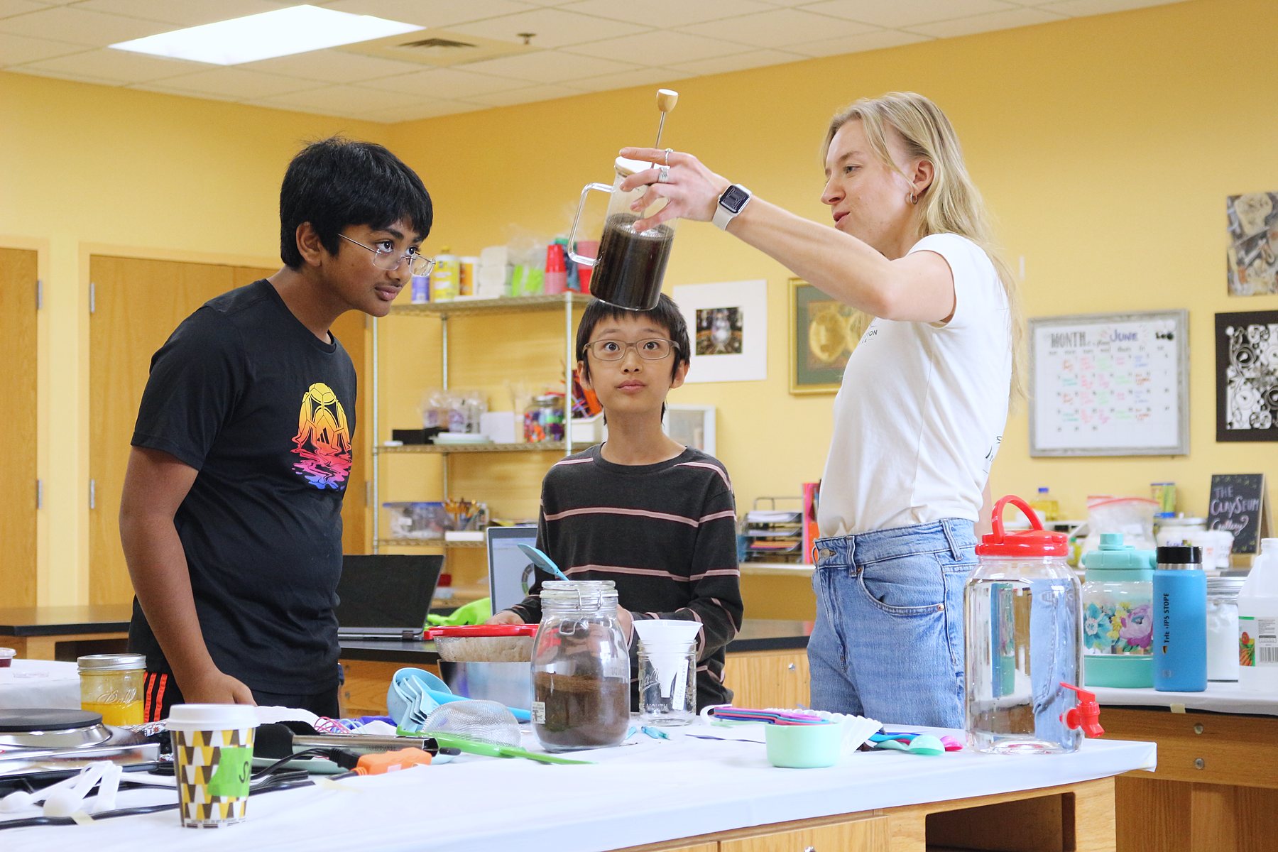 An instructor holds a jar of natural dye up to the light while students watch