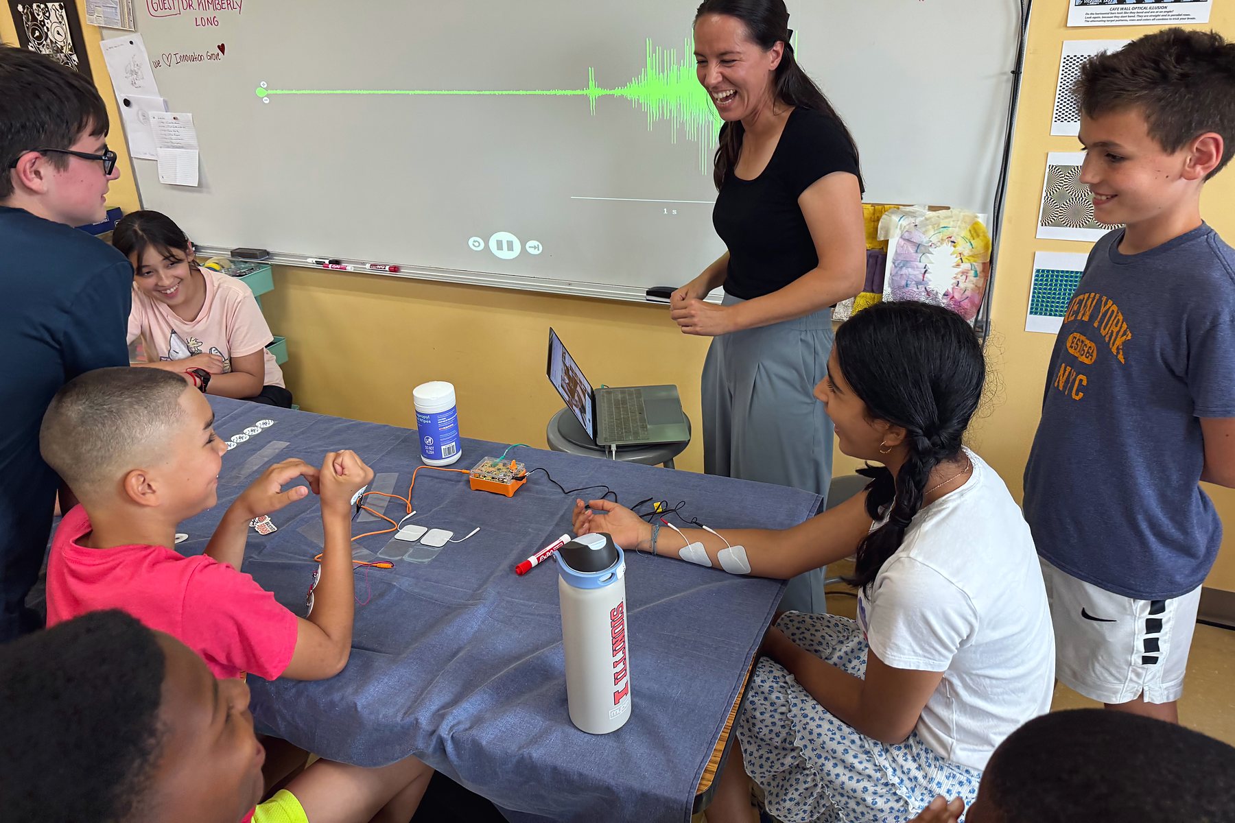 Brain Time: a spike recorder traces muscle signals on the screen while an instructor laughs with students